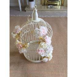 Cream ornamental bird cage with pale flowers attached. Used for a wedding.