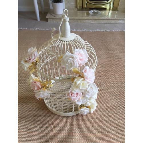 Cream ornamental bird cage with pale flowers attached. Used for a wedding.
