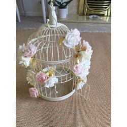 Cream ornamental bird cage with pale flowers attached. Used for a wedding.
