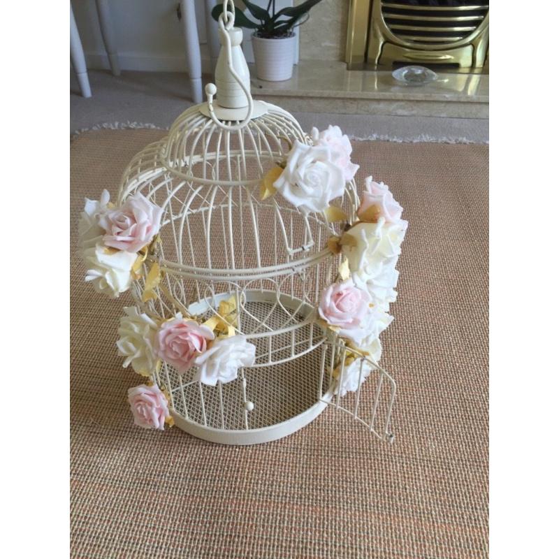 Cream ornamental bird cage with pale flowers attached. Used for a wedding.